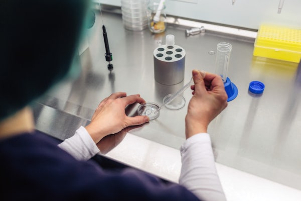 A biologist adds an unknown liquid to a petri dish using a long dropper.